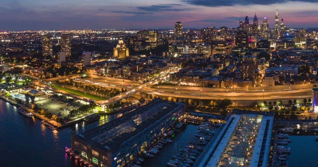 Philadelpia Downtown at sunset. The view from the Benjamin Franklin Bridge over the piers in Old City and Delaware River. Pennsylvania, USA.