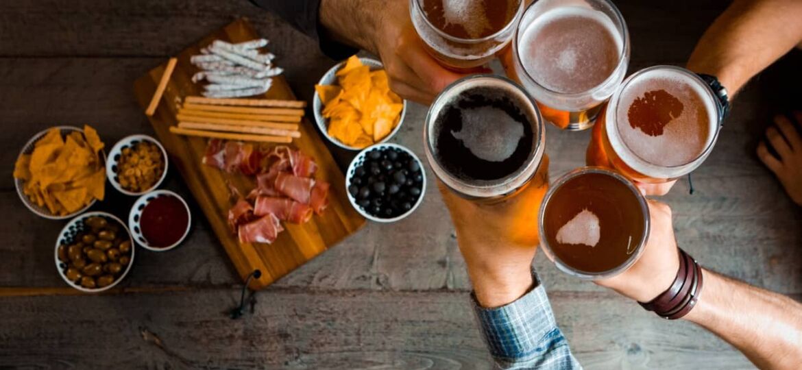 Top view of friends toasting with beer glasses in the pub