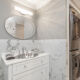 Luxury bathroom with elegant lighting and white vanity with stackable in-unit washer and dryer in Philly condo for sale