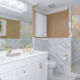 Double sinks with gold faucets and white vanitys in front of large mirror in luxury condominium bathroom