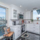 Stunning open kitchen with white cabinetry, stainless steel appliances, and sliding glass door with Philadelphia skyline